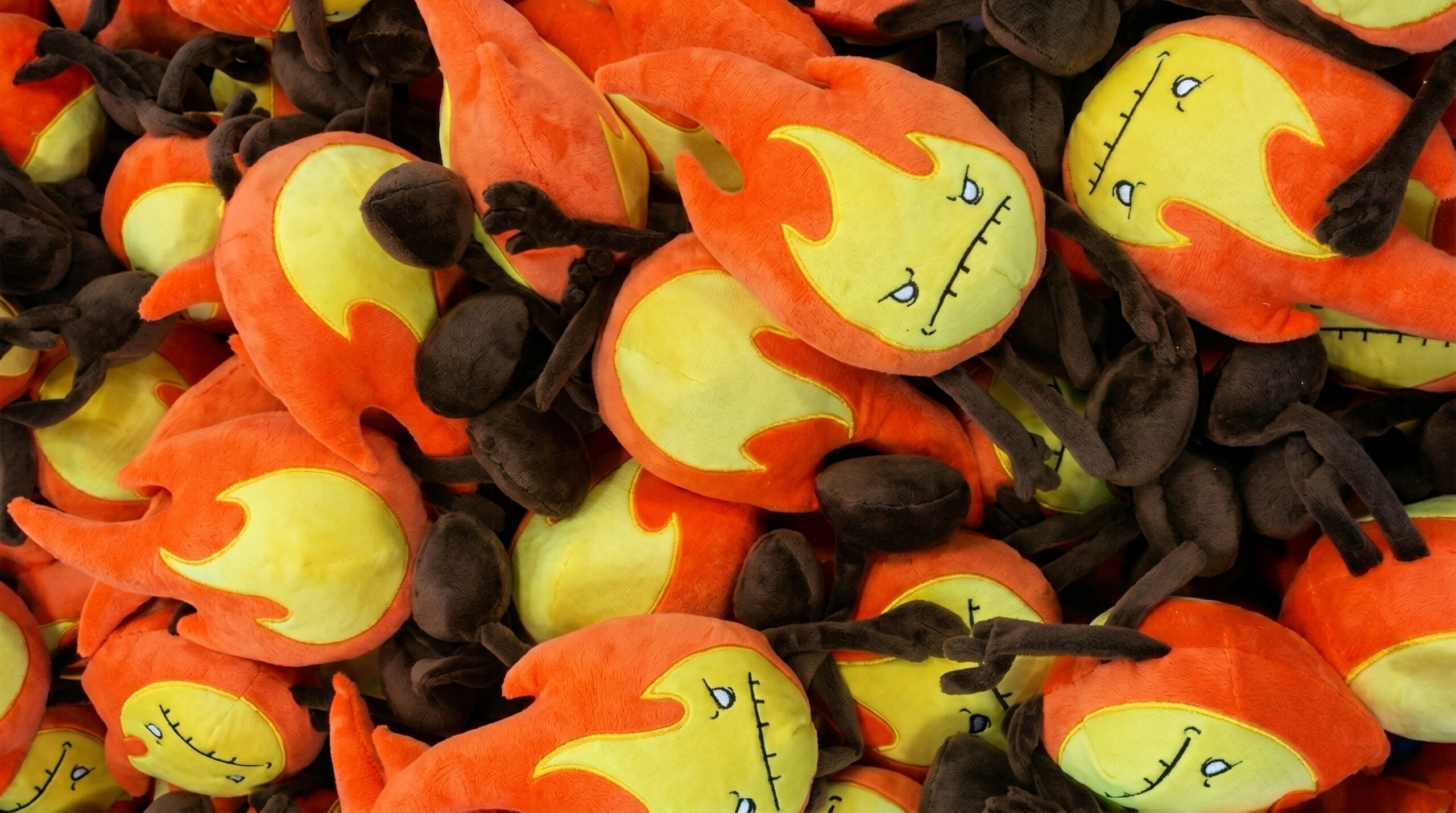 A large pile of finished orange fire plushies from the first Fire Element Plush Production batch for the Raven Stitch Kickstarter.
