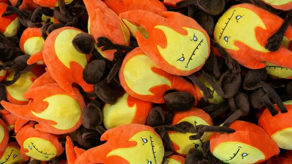 A large pile of finished orange fire plushies from the first Fire Element Plush Production batch for the Raven Stitch Kickstarter.