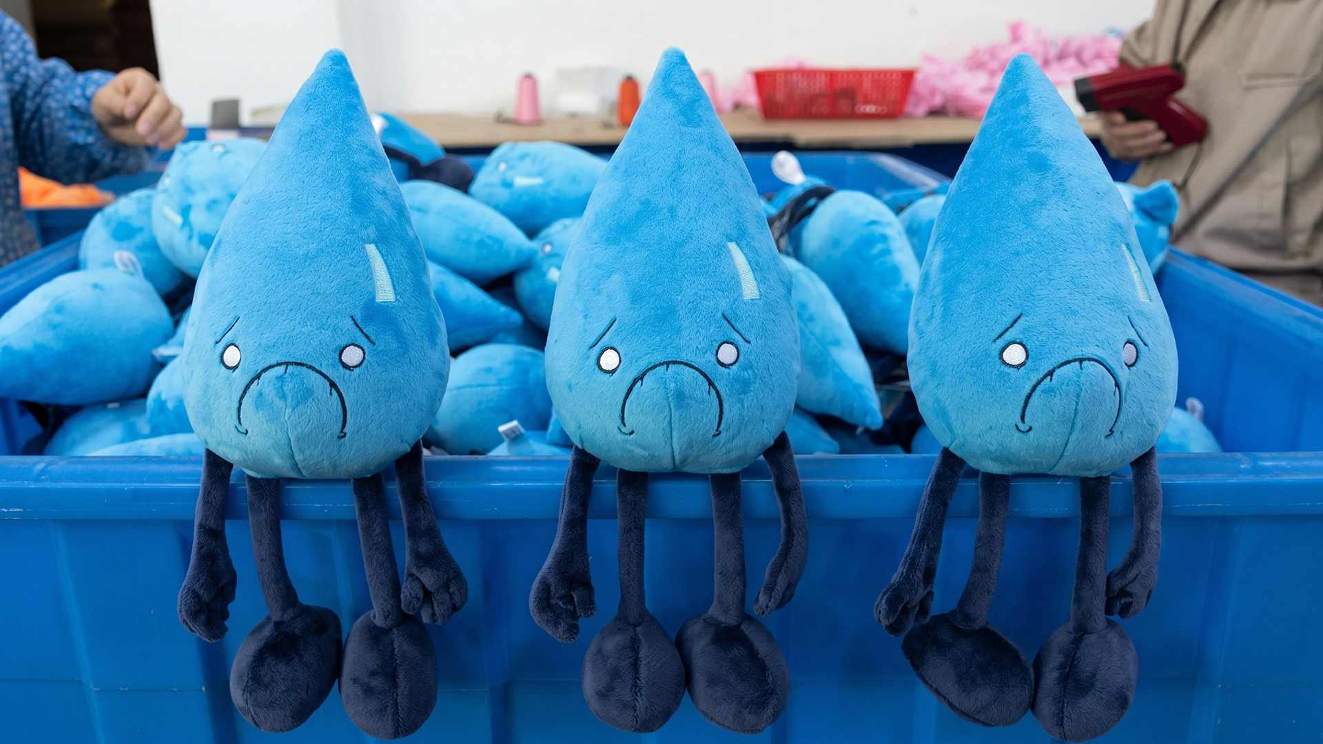 A dense pile of blue Water Element plush toys with sad, nervous expressions and dark blue limbs, shown during the final stages of production.