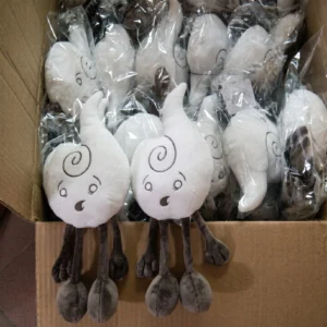 Two white Air element plush toys with swirl designs and surprised expressions sitting on a cardboard box filled with more plushies individually wrapped in plastic.