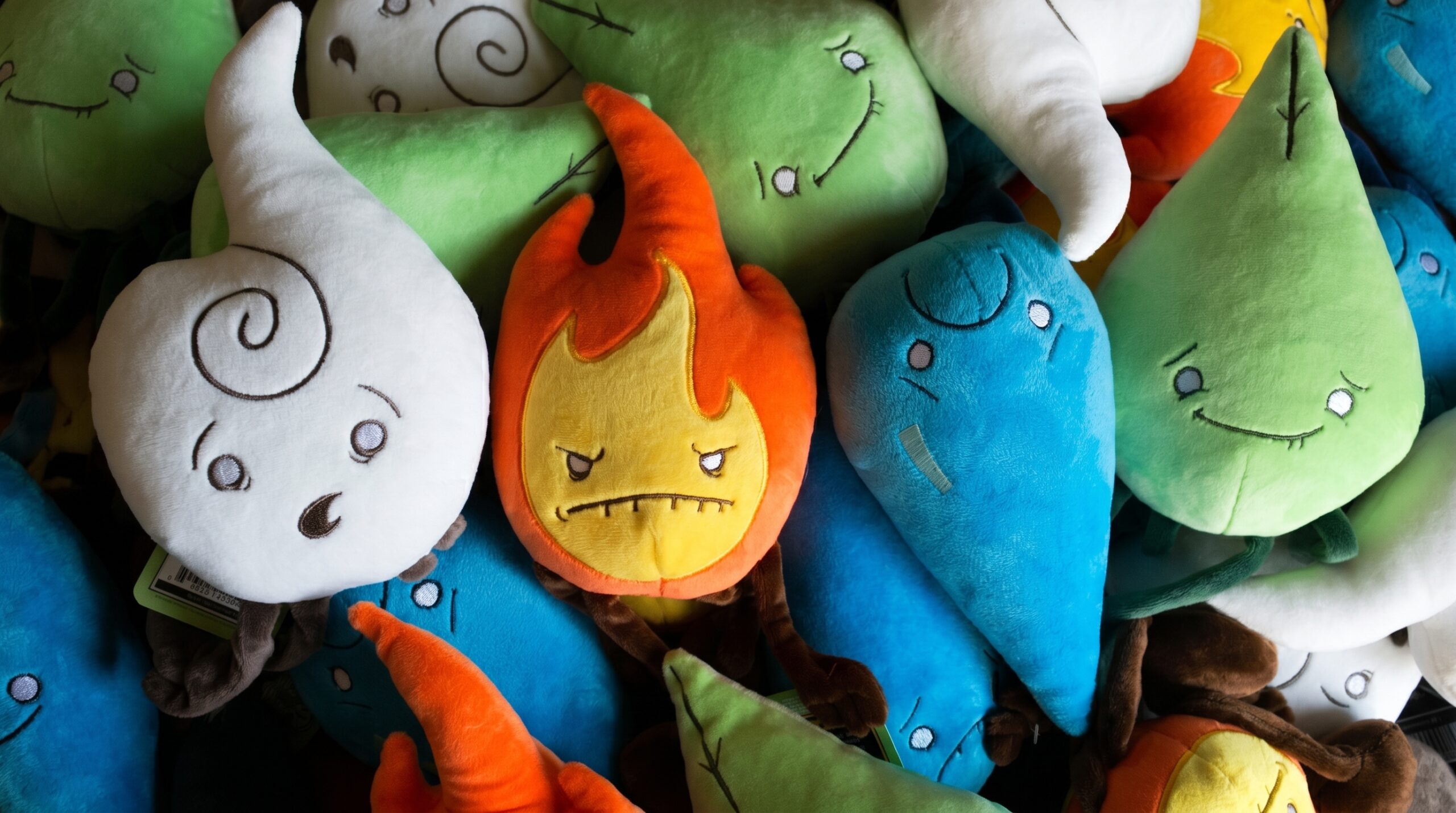 A colorful pile featuring the full collection of Raven Stitch Plush Elements: the grumpy orange Fire, the nervous blue Water, the smiling green Earth, and the surprised white Air spirits.
