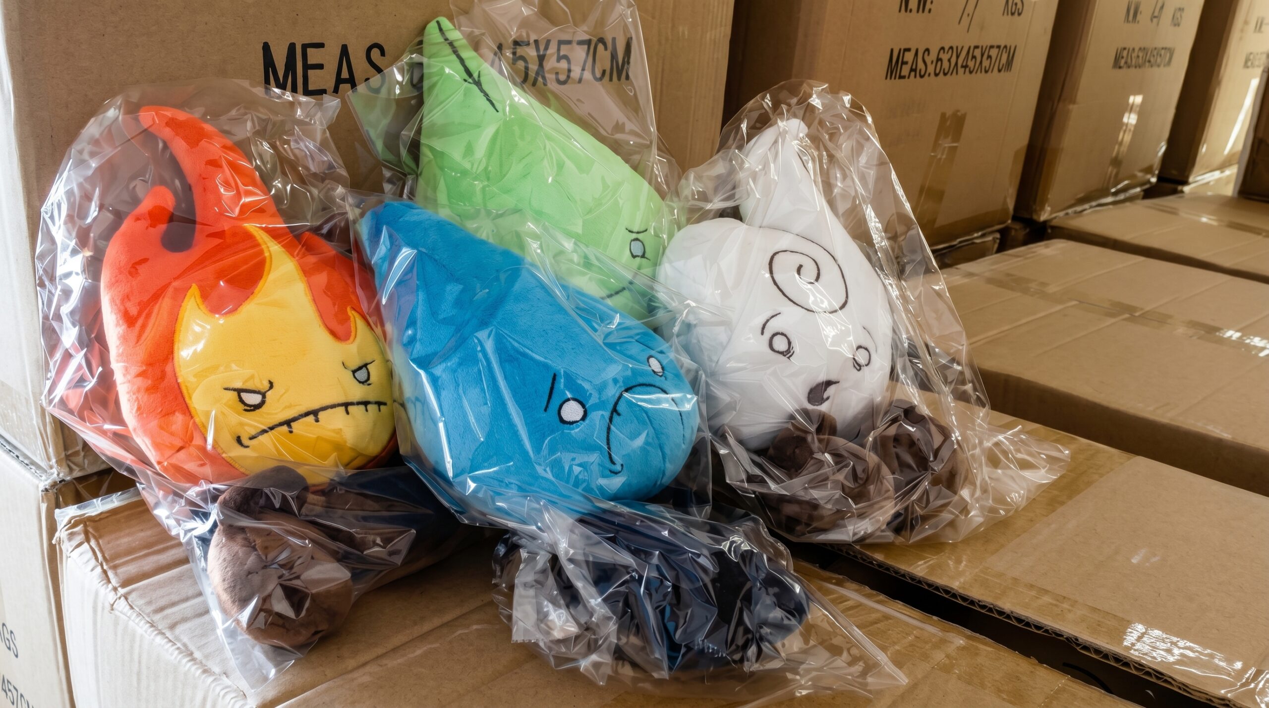 Individually bagged Fire, Water, Earth, and Air plush toys sitting on top of large cardboard shipping boxes in a storage facility.